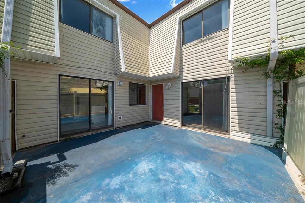 A small concrete patio sits between two sections of a two-story beige vinyl-sided house — 2142 NE 45TH AVENUE UNIT 2, OCALA, FL