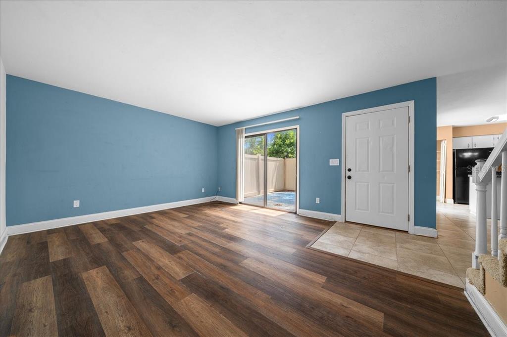 A living room features blue walls, wood-look flooring, a sliding glass door, and an entryway — 2142 NE 45TH AVENUE UNIT 2, OCALA, FL