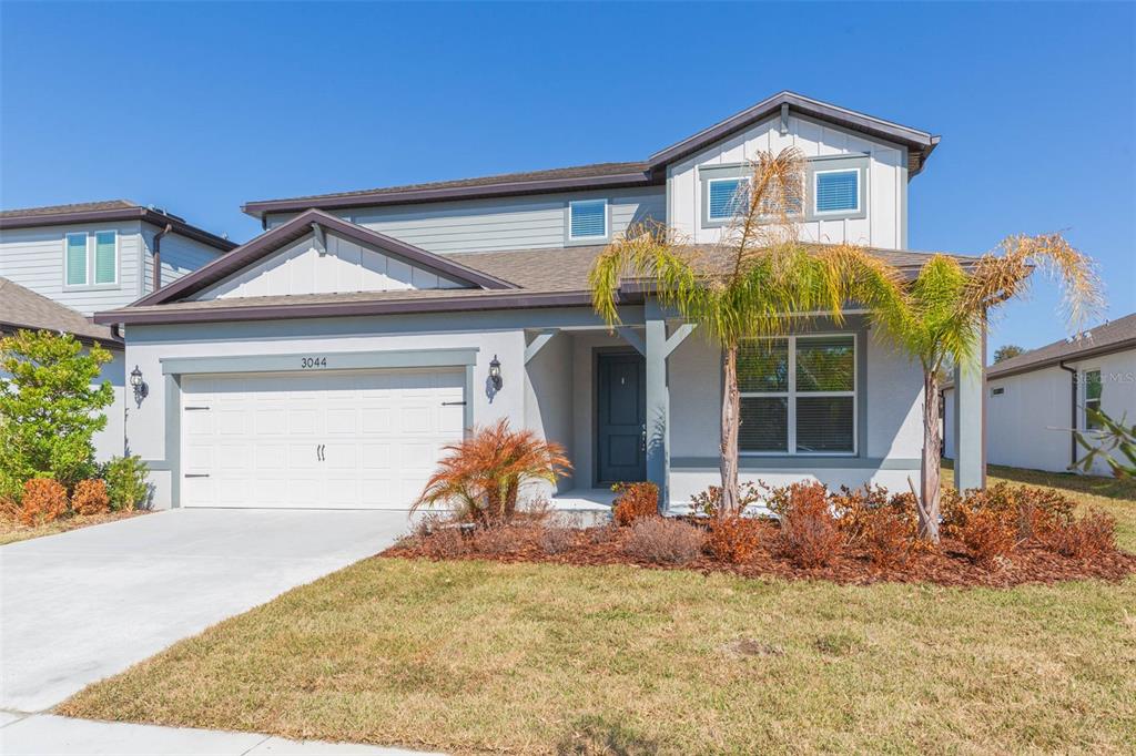 A two-story suburban house with a gray stucco exterior, a two-car garage, and palm trees — 3044 FOREST MEADOW AVENUE, VALRICO, FL