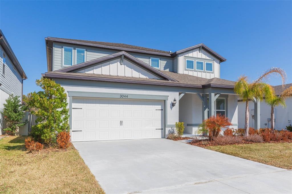 A two-story suburban house features a white garage, gray siding, and a concrete driveway — 3044 FOREST MEADOW AVENUE, VALRICO, FL
