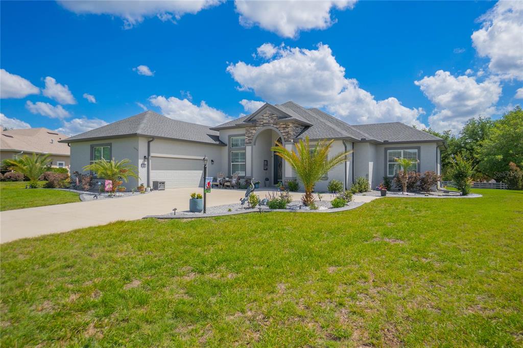 A single-story suburban house with a stone-accented entryway, a two-car garage, and a landscaped yard — 1555 E SEATTLE SLEW CIRCLE, INVERNESS, FL