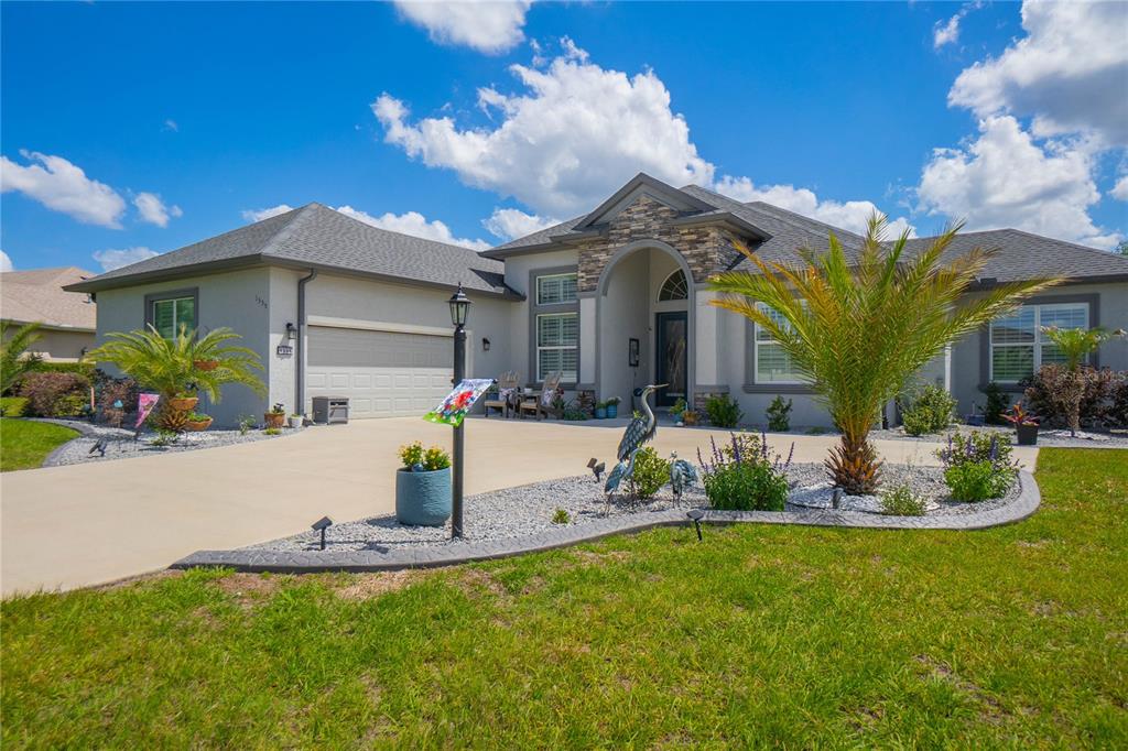 A single-story house with a stone-accented entryway, a two-car garage, and a landscaped front yard — 1555 E SEATTLE SLEW CIRCLE, INVERNESS, FL
