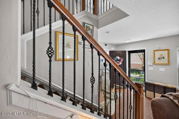 A staircase with black metal balusters and a wooden handrail leads to an upper level — 541 CABERNET, ST AUGUSTINE, FL