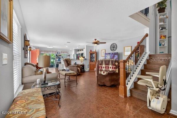 An open-concept living room features tile flooring, a staircase with a lift, and kitchen access — 541 CABERNET, ST AUGUSTINE, FL