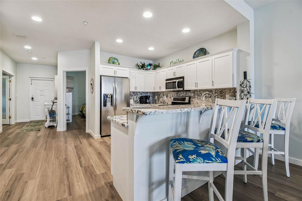 A kitchen features white cabinets, granite countertops, stainless steel appliances, and a breakfast bar — 530 S GULFVIEW BOULEVARD UNIT 304, CLEARWATER BEACH, FL