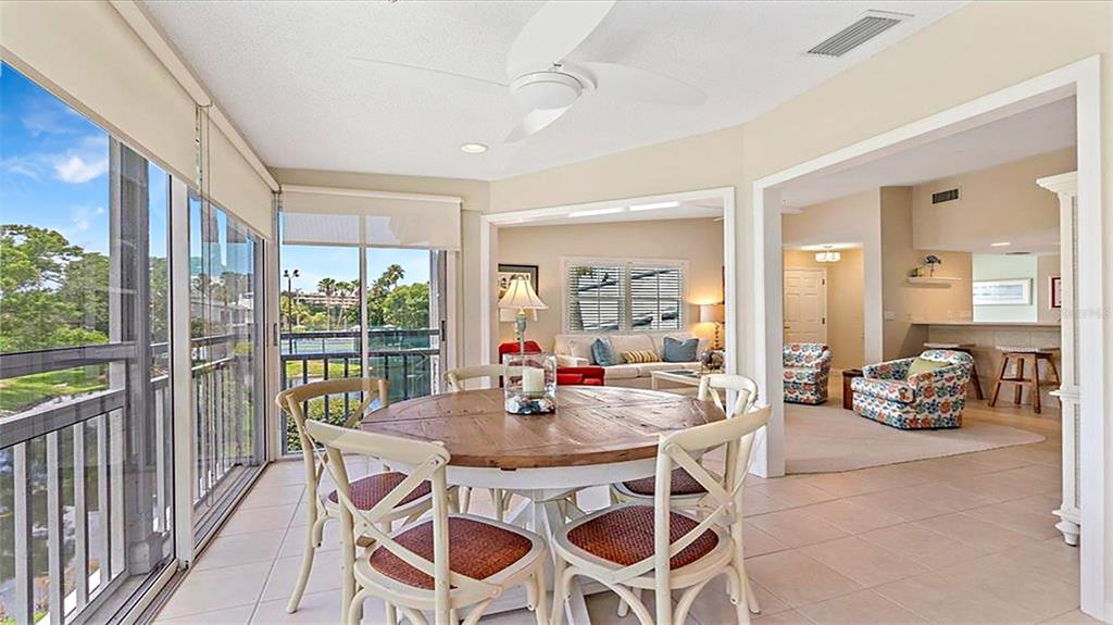 A sunroom with a round dining table leads into a living area and kitchen — 1274 SIESTA BAYSIDE DRIVE UNIT 1274-C, SARASOTA, FL