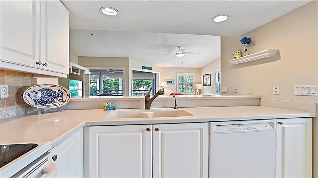 A kitchen features white cabinets, a double sink, and a view into the living area — 1274 SIESTA BAYSIDE DRIVE UNIT 1274-C, SARASOTA, FL