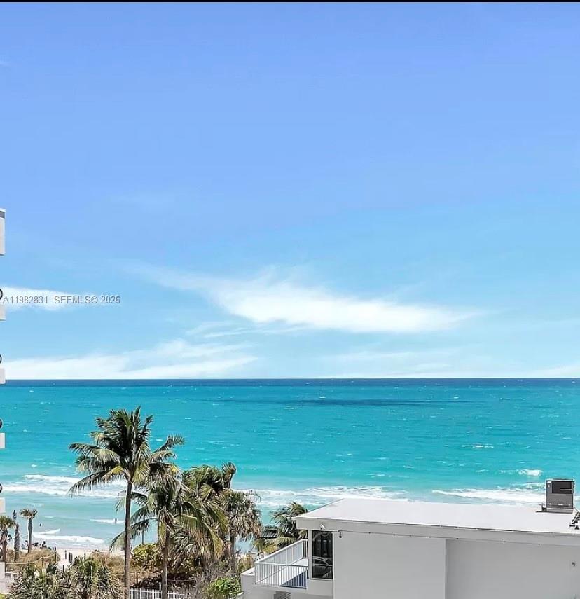 An elevated view of a turquoise ocean, sandy beach, palm trees, and a building rooftop — 5401 Collins Ave # 411, Miami Beach FL 33140, MIAMI BEACH, FL