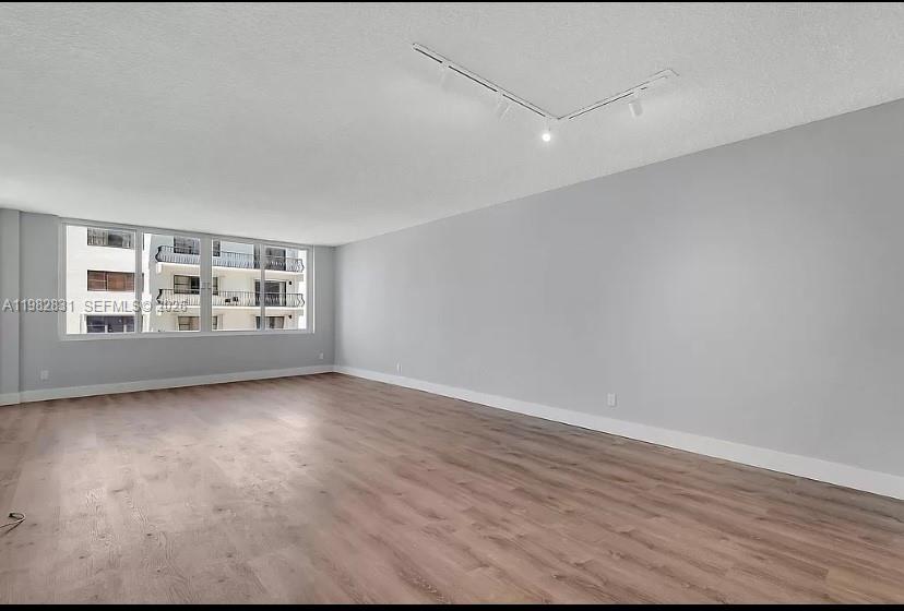 An empty room with light wood-look flooring, gray walls, and a ceiling-mounted track light — 5401 Collins Ave # 411, Miami Beach FL 33140, MIAMI BEACH, FL