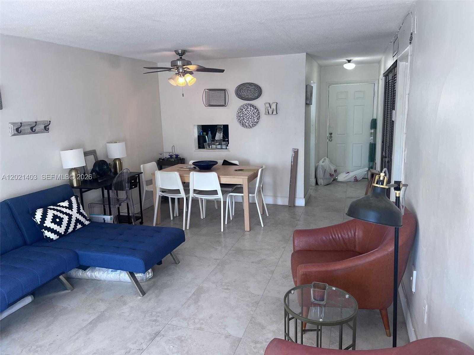 A living and dining area features tile floors, a blue sofa, and a brown armchair — 528 Meridian Ave # 503, Miami Beach FL 33139, MIAMI BEACH, FL