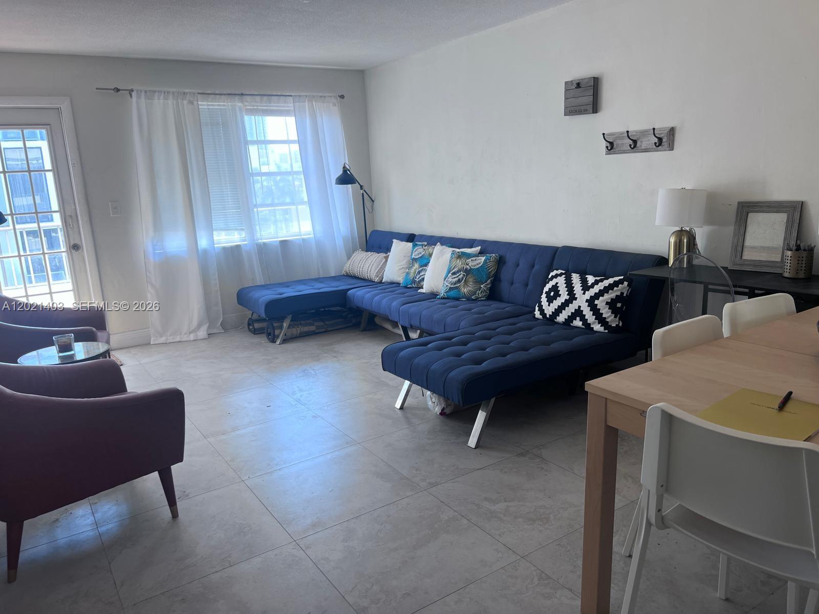 A living room features a blue sectional sofa, tile flooring, and a dining area — 528 Meridian Ave # 503, Miami Beach FL 33139, MIAMI BEACH, FL