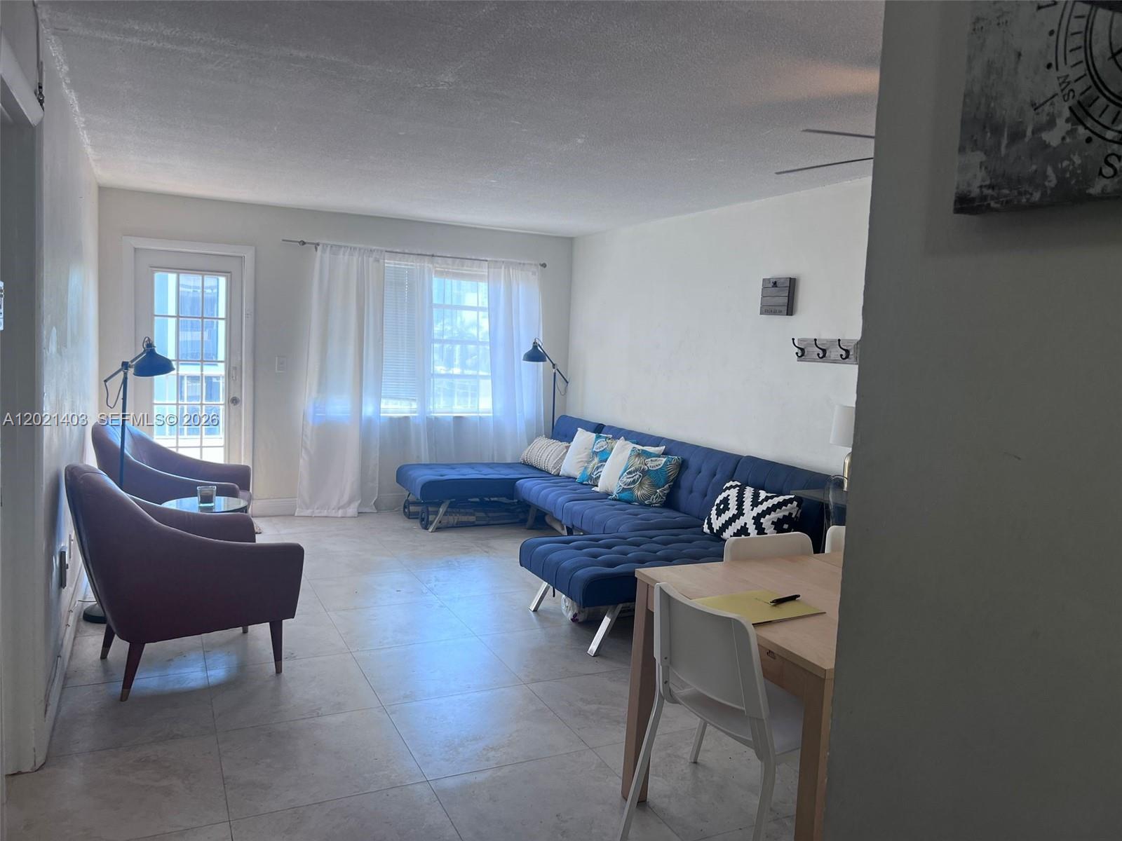 A living room features a blue sectional sofa, two purple armchairs, and tile flooring — 528 Meridian Ave # 503, Miami Beach FL 33139, MIAMI BEACH, FL