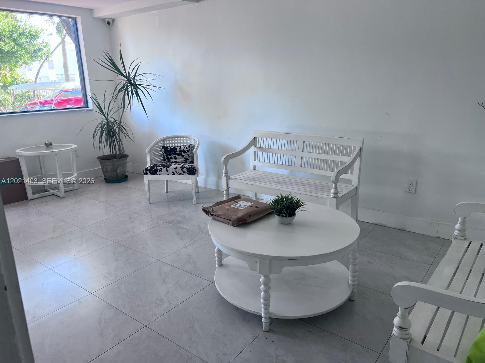 A bright room features white wooden benches, a round coffee table, and a potted plant — 528 Meridian Ave # 503, Miami Beach FL 33139, MIAMI BEACH, FL