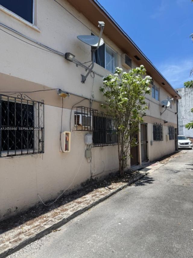 The exterior of a two-story apartment building features stucco walls, metal window grilles, and satellite dishes — 927 NW 7th Ct # 2, Miami FL 33136, MIAMI, FL