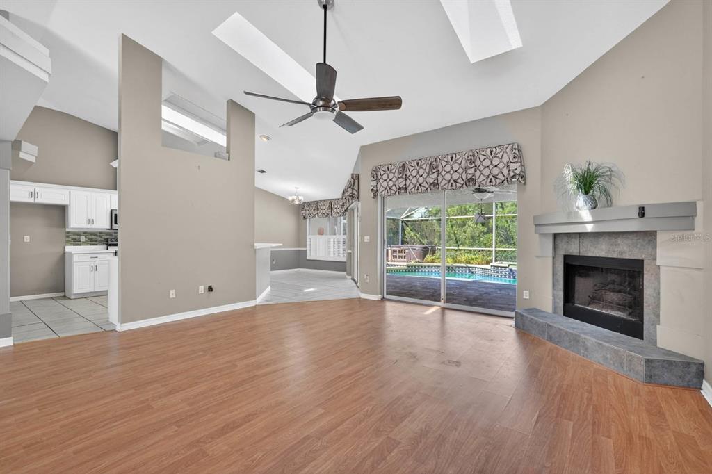 A living room with wood-look flooring, a fireplace, and sliding glass doors to a pool — 5988 SHADY CREEK LANE, PORT ORANGE, FL