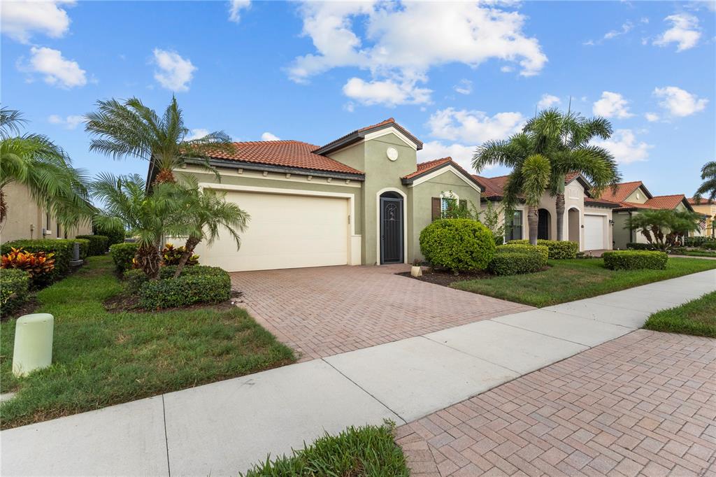 A single-story house with a terracotta tile roof, beige stucco walls, and a paved driveway — 24252 GALLBERRY DRIVE, VENICE, FL