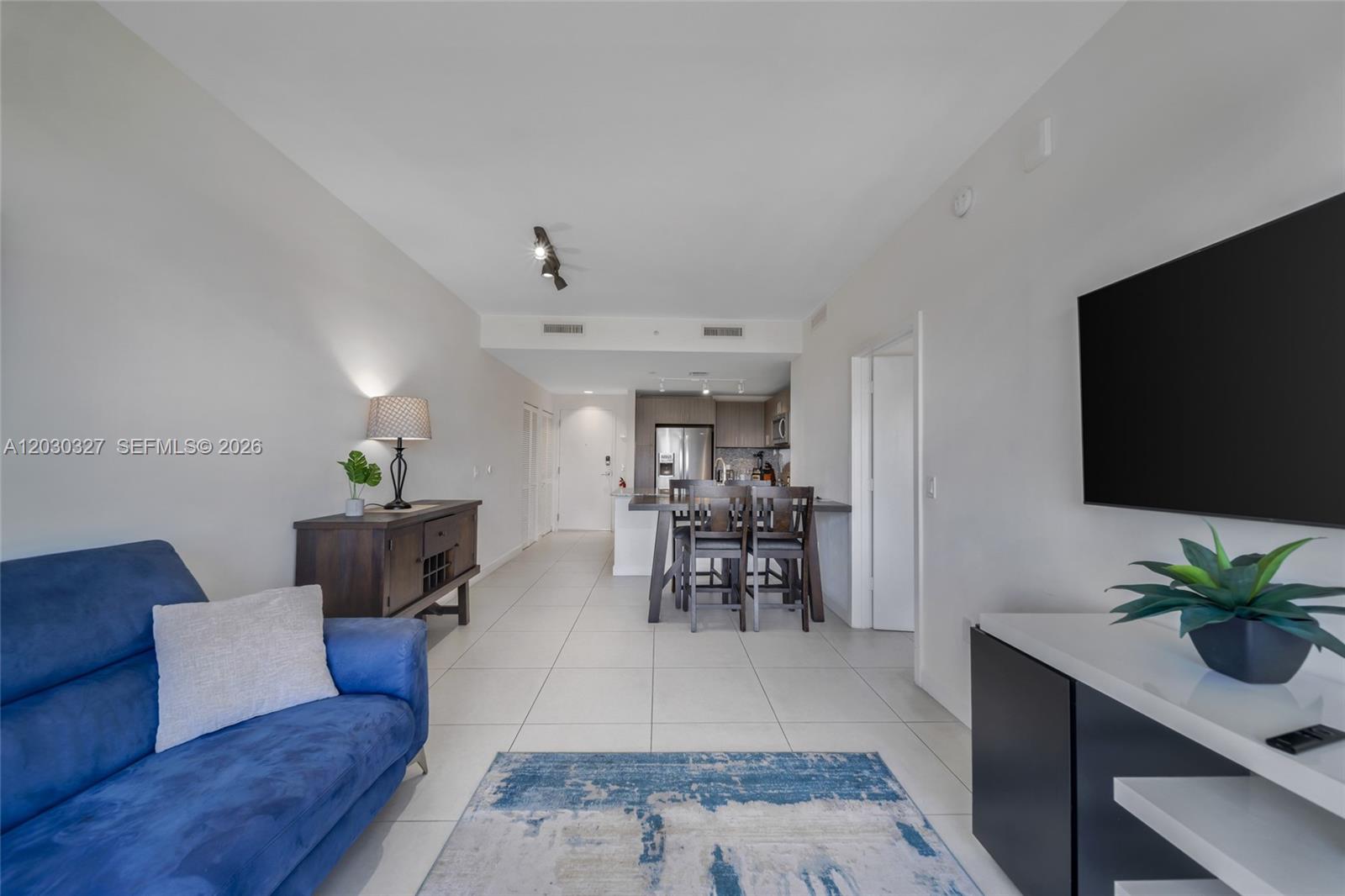 A living room with a blue sofa and dining area features tile flooring throughout — 5350 NW 84th Ave # 903, Doral FL 33166, DORAL, FL