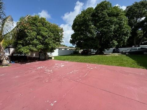 A large red concrete driveway leads to a grassy yard with mature trees and cars — 735 NE 152nd St, Miami FL 33162, MIAMI, FL