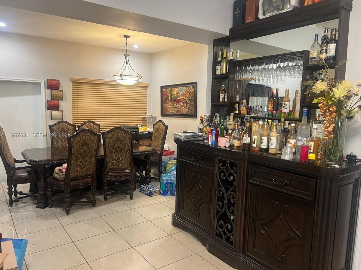 A dining room features a large wooden bar cabinet and a table with ornate chairs — 735 NE 152nd St, Miami FL 33162, MIAMI, FL