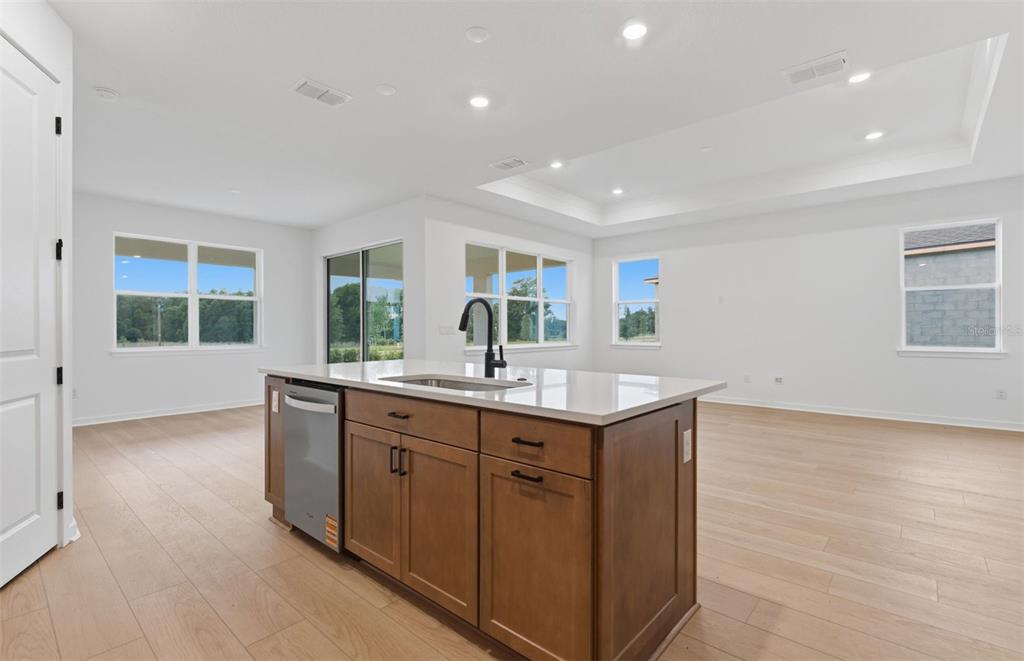 A kitchen island with a sink and dishwasher sits in a room with light flooring — 33456 HERDS HALLOW WAY, WESLEY CHAPEL, FL
