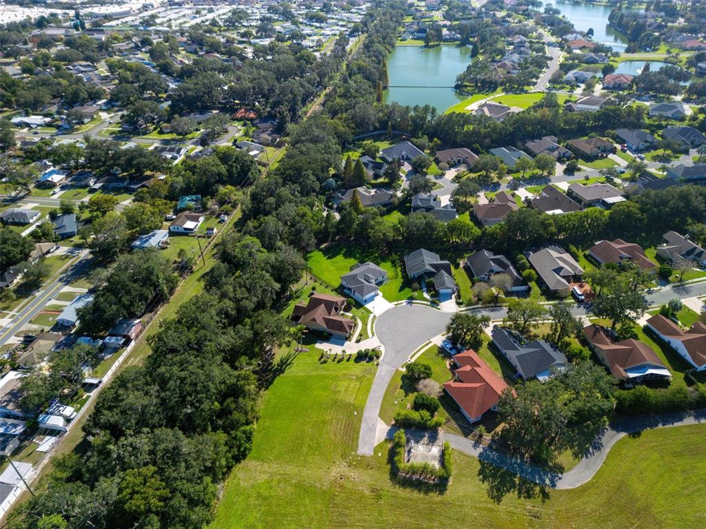 An aerial view shows a suburban neighborhood with houses, green lawns, and a small lake — 3160 OAKPARK DRIVE, LAKELAND, FL