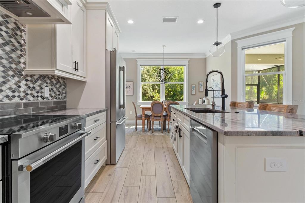 A modern kitchen features white cabinetry, stainless steel appliances, a large island, and wood-look flooring — 3160 OAKPARK DRIVE, LAKELAND, FL