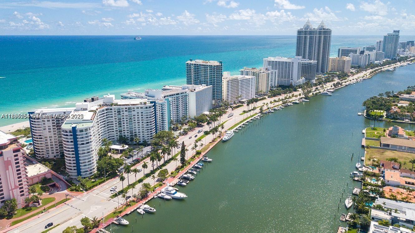 An aerial view shows high-rise buildings along a beach and a canal with boats — 5161 Collins Ave # 1211, Miami Beach FL 33140, MIAMI BEACH, FL