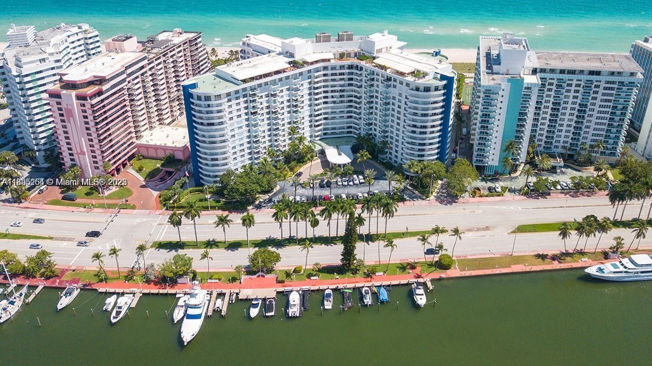 An aerial view shows a curved residential building situated between a coastal road and beach — 5161 Collins Ave # 1211, Miami Beach FL 33140, MIAMI BEACH, FL
