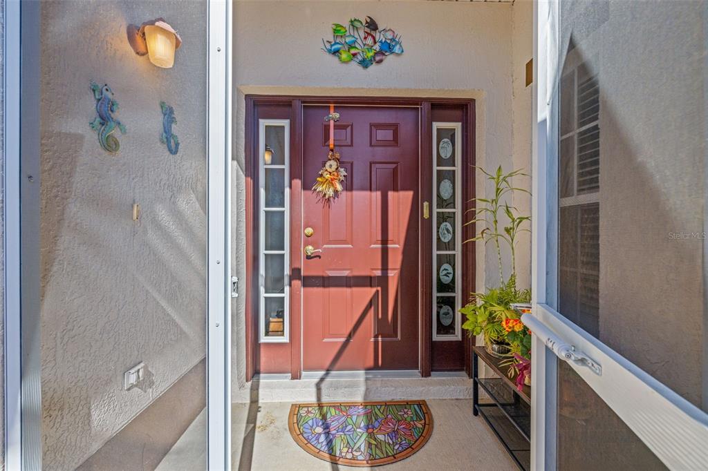 A front entryway features a red door with sidelights, a decorative rug, and wall art — 29335 CADDY SHACK LANE E, SAN ANTONIO, FL