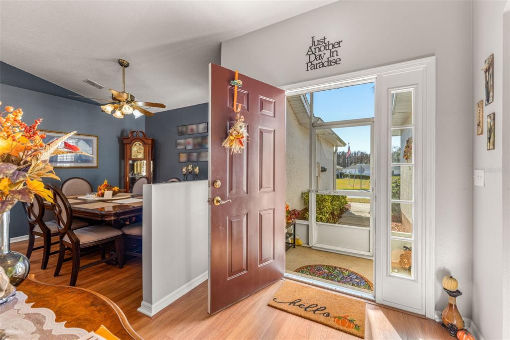 An open front door reveals a dining area with wood floors and a view outside — 29335 CADDY SHACK LANE E, SAN ANTONIO, FL