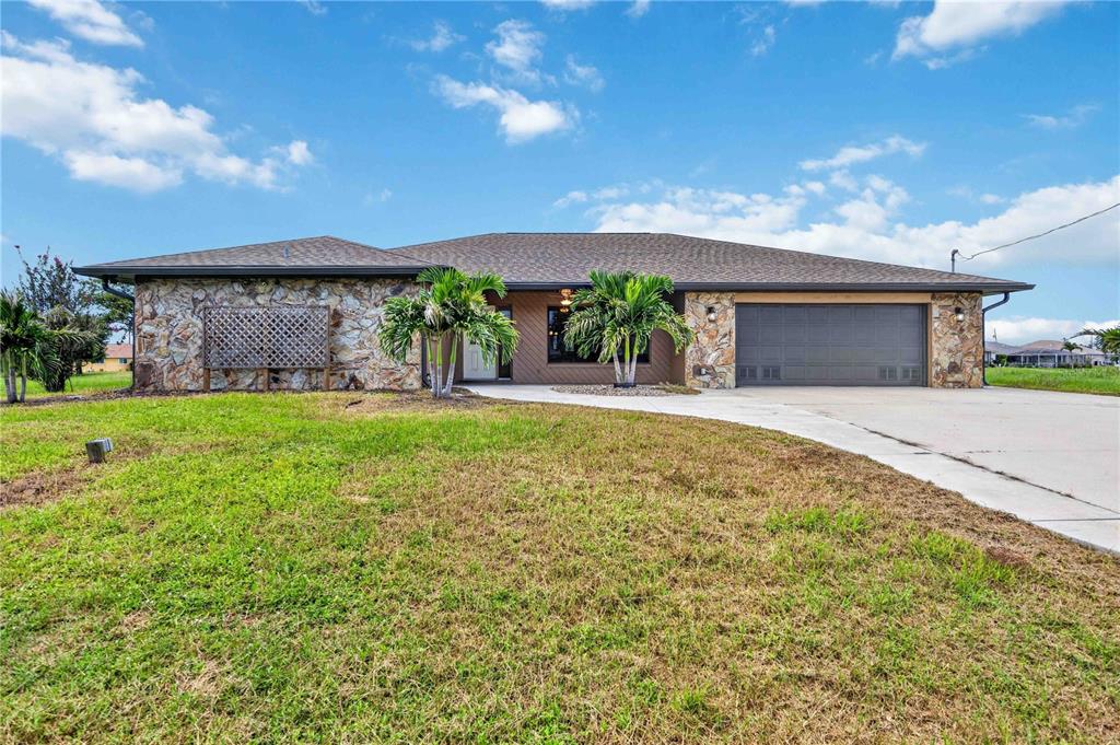 A single-story house with a stone facade, a two-car garage, and palm trees in front — 166 MARK TWAIN LANE, ROTONDA WEST, FL