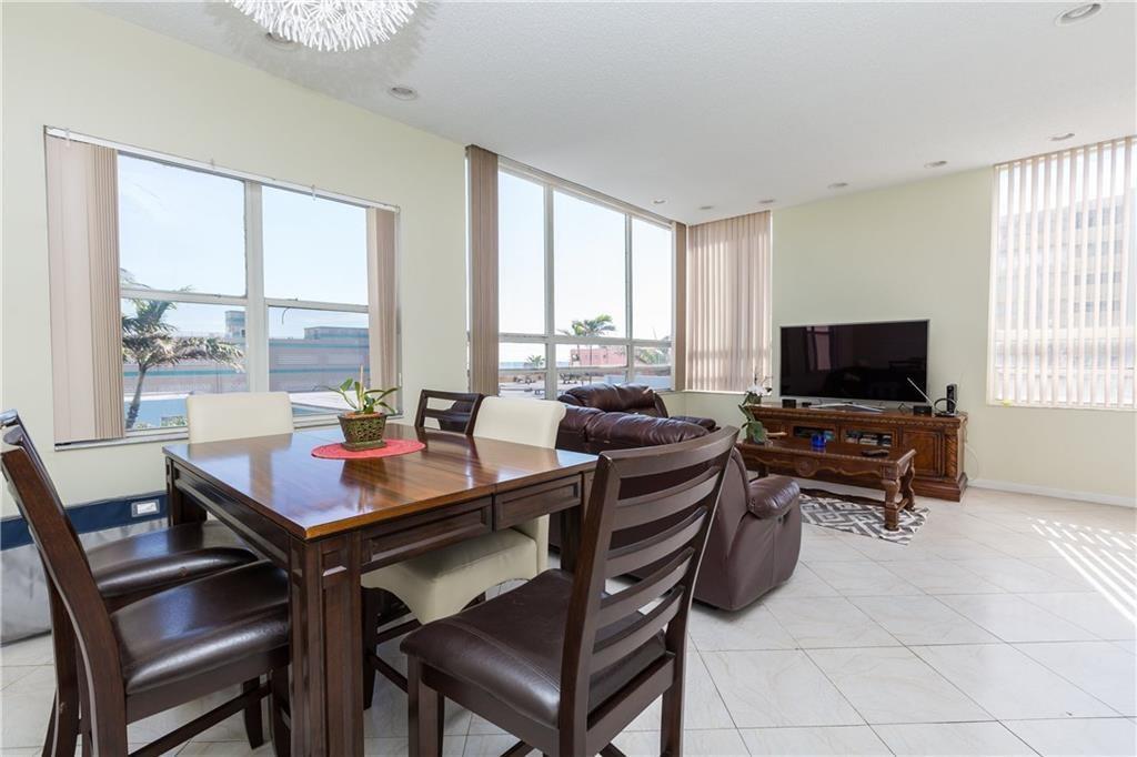 A dining area and living room with tile floors, large windows, and dark wood furniture — 326 Harrison Street # 302a, Hollywood FL 33019, HOLLYWOOD, FL