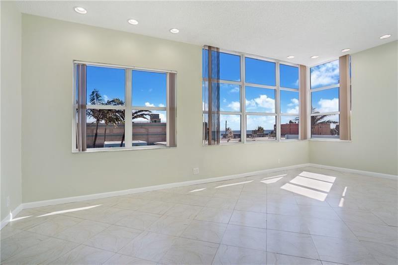 An empty room with light-colored tile flooring, recessed lighting, and large windows overlooking the ocean — 326 Harrison Street # 302a, Hollywood FL 33019, HOLLYWOOD, FL