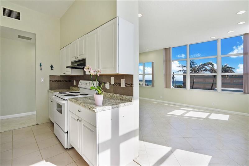 A kitchen with white cabinets and granite countertops opens into a bright living area — 326 Harrison Street # 302a, Hollywood FL 33019, HOLLYWOOD, FL