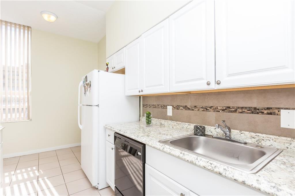 A kitchen features white cabinets, granite countertops, a stainless steel sink, and a white refrigerator — 326 Harrison Street # 302a, Hollywood FL 33019, HOLLYWOOD, FL