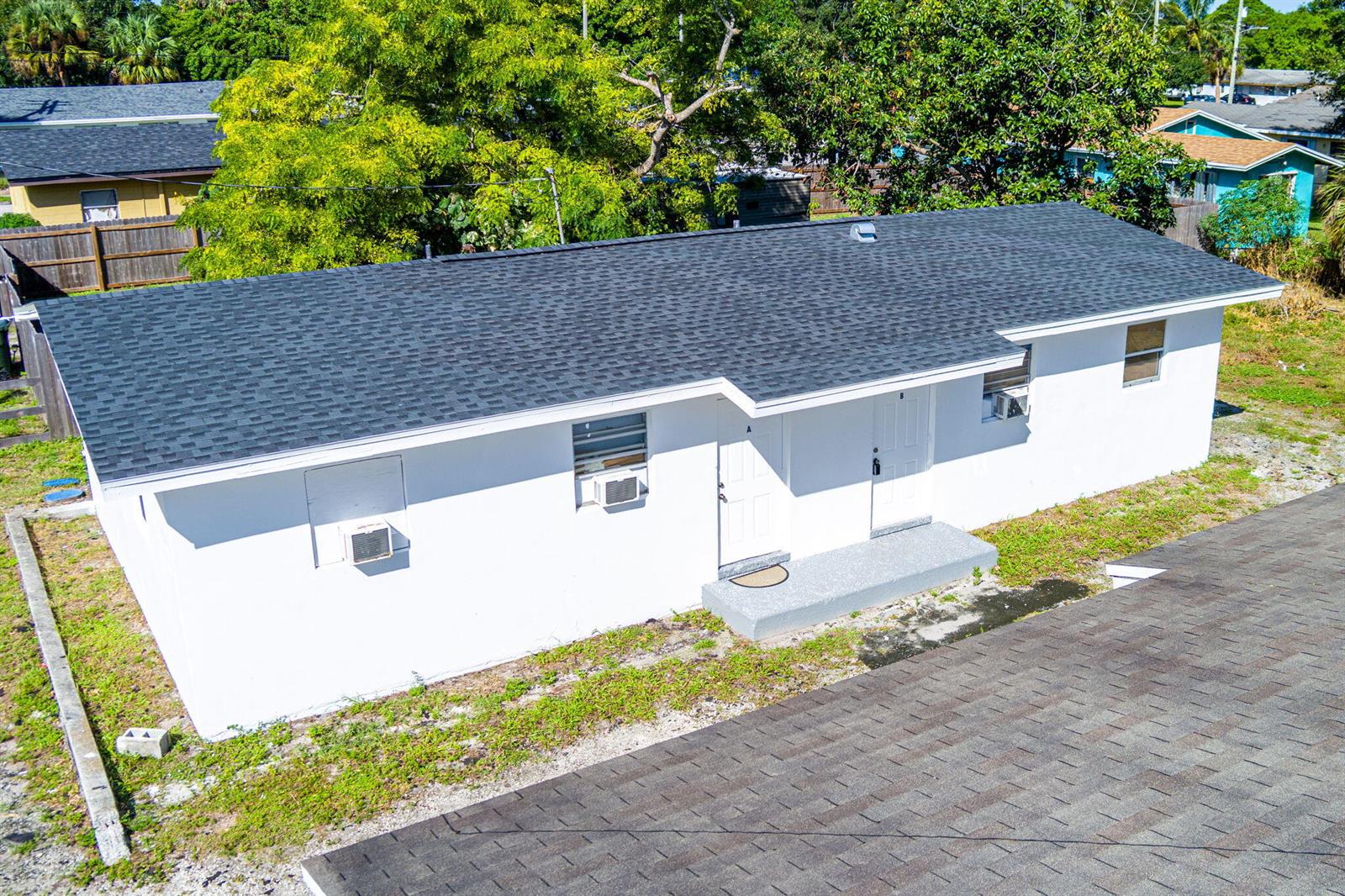 An aerial view of a white, single-story duplex with a dark shingled roof — 2108 Avenue E, Fort Pierce FL 34950, FORT PIERCE, FL