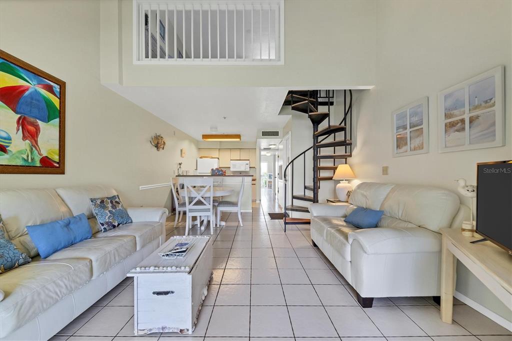 A living room with white sofas, a spiral staircase, and a dining area in the background — 9400 LITTLE GASPARILLA ISLAND UNIT E2, PLACIDA, FL