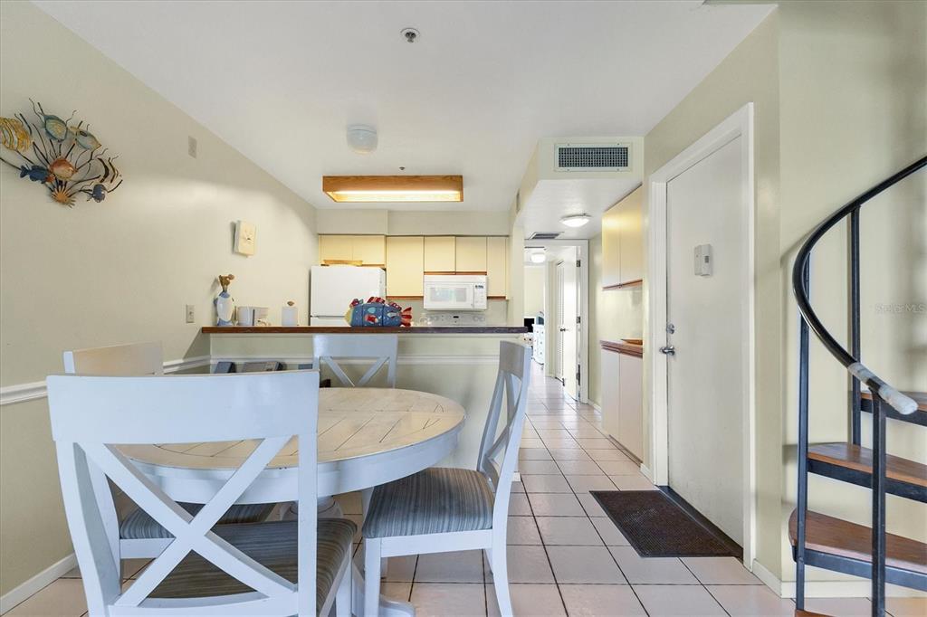 A dining area with a round table and chairs sits before a kitchen with cabinets — 9400 LITTLE GASPARILLA ISLAND UNIT E2, PLACIDA, FL