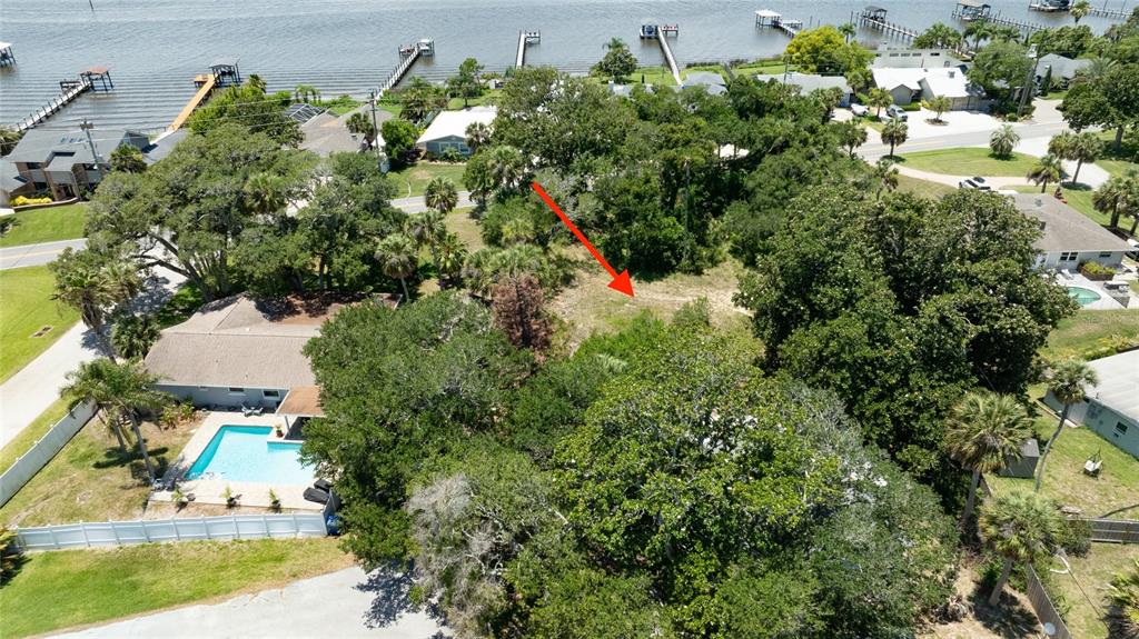 An aerial view shows a vacant, tree-covered lot situated between two residential properties near water — 1287 JOHN ANDERSON DRIVE, ORMOND BEACH, FL