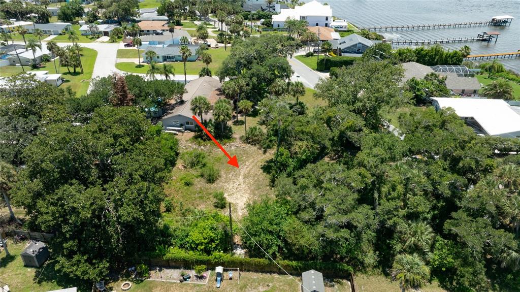 An aerial view shows a vacant, wooded residential lot with a red arrow pointing downward — 1287 JOHN ANDERSON DRIVE, ORMOND BEACH, FL