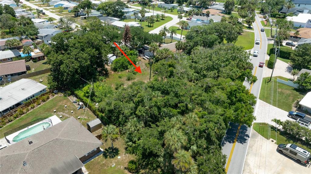 An aerial view shows a vacant, tree-covered residential lot next to a house with a pool — 1287 JOHN ANDERSON DRIVE, ORMOND BEACH, FL