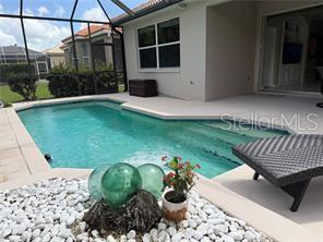 A swimming pool with a screened enclosure sits next to a house with a patio — 6288 WINGSPAN WAY, BRADENTON, FL