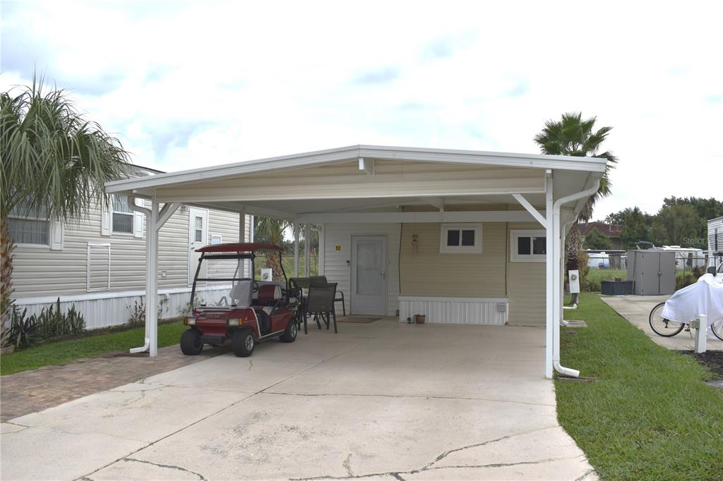 A manufactured home features a large carport, a concrete driveway, and a parked golf cart — 9000 US HWY 192 UNIT 52, CLERMONT, FL
