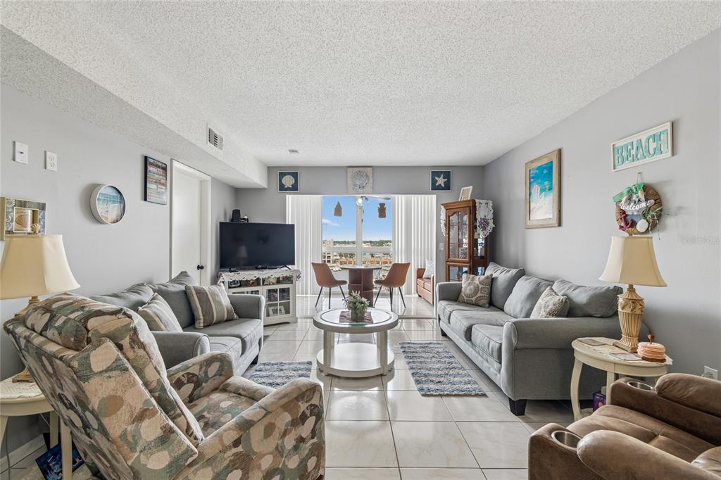 A living room features light tile floors, two grey sofas, and a view of water — 4939 FLORAMAR TERRACE UNIT 610, NEW PORT RICHEY, FL