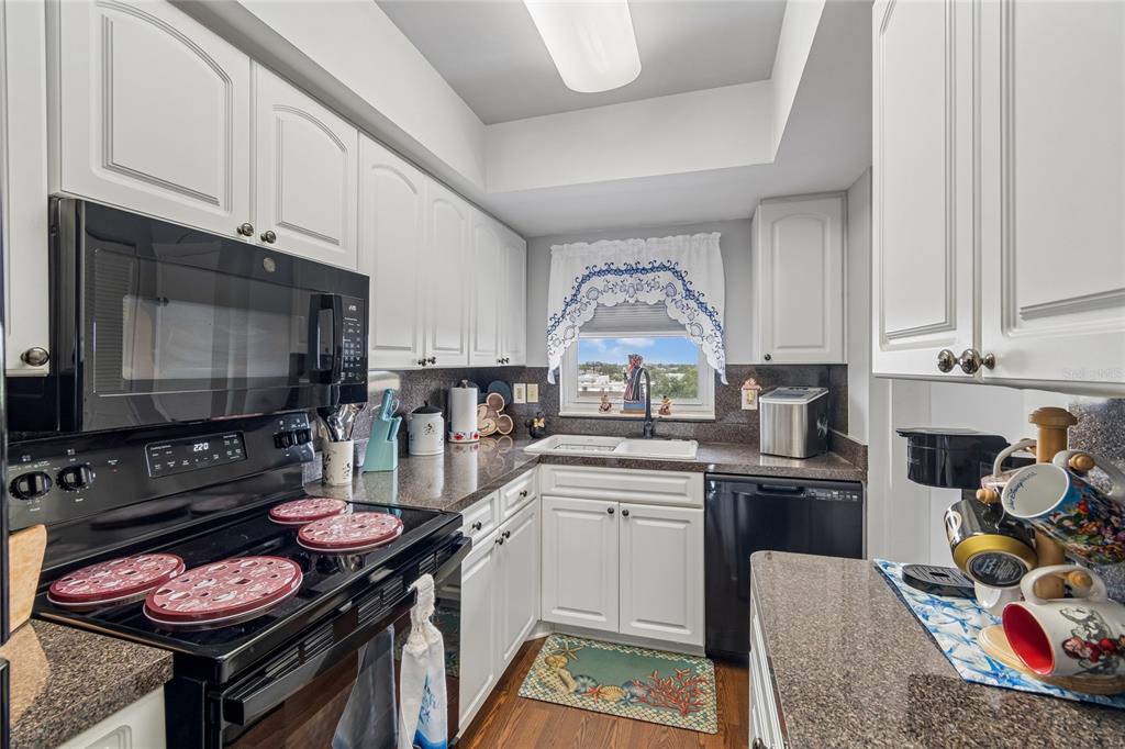 A kitchen with white cabinets, black appliances, granite countertops, and a window above the sink — 4939 FLORAMAR TERRACE UNIT 610, NEW PORT RICHEY, FL
