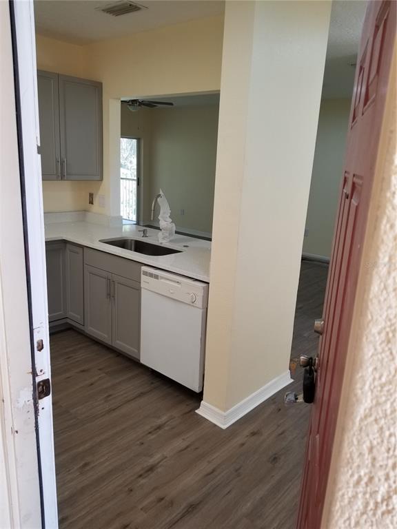 A kitchen features gray cabinets, a white dishwasher, and wood-look flooring — 6022 PORTSDALE PLACE UNIT 202, RIVERVIEW, FL