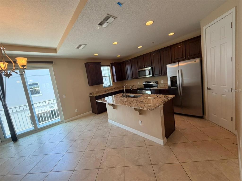A kitchen features dark wood cabinets, granite countertops, a center island, and stainless steel appliances — 1162 BOLTON PLACE, LAKE MARY, FL
