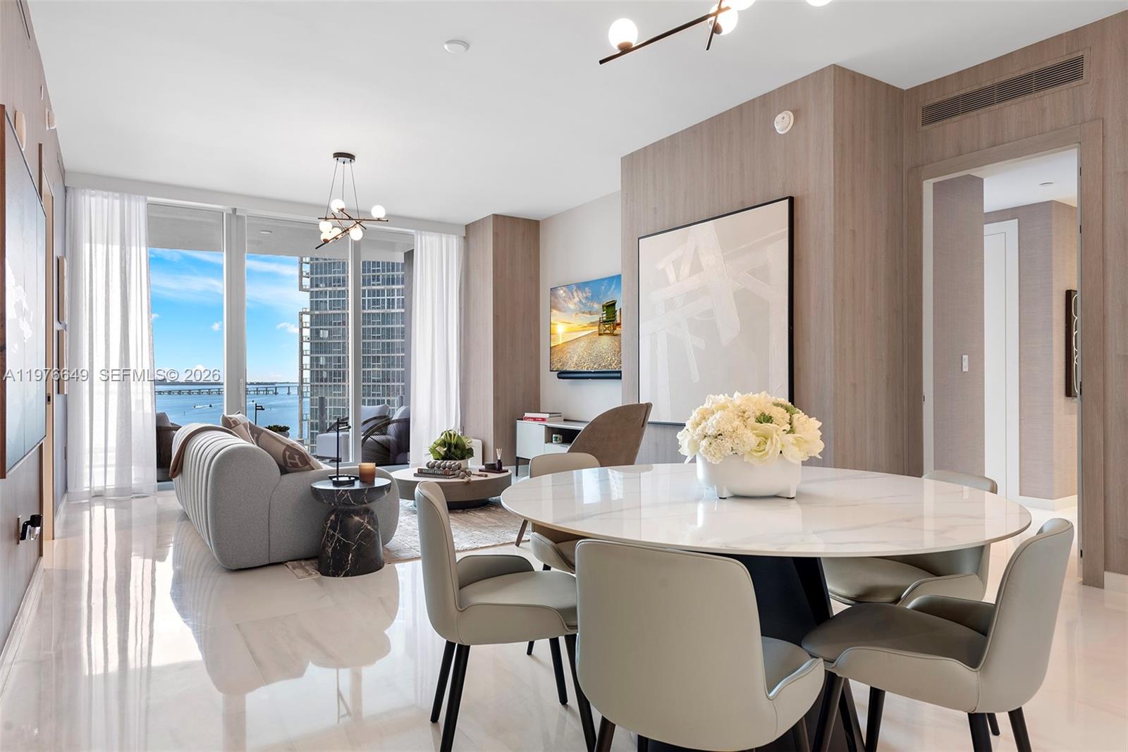 A modern living and dining area features a marble table, gray sofa, and balcony views — 300 Biscayne Blvd Way # 1605, Miami FL 33131, MIAMI, FL