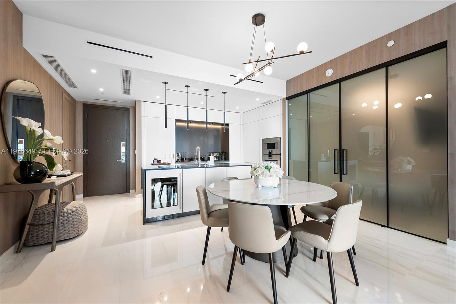A modern kitchen and dining area feature a white island, marble table, and glass doors — 300 Biscayne Blvd Way # 1605, Miami FL 33131, MIAMI, FL