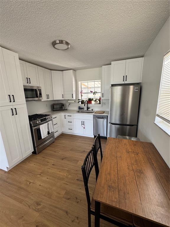 A kitchen features white cabinets, stainless steel appliances, and wood-look flooring — 631 75TH AVENUE N, ST PETERSBURG, FL